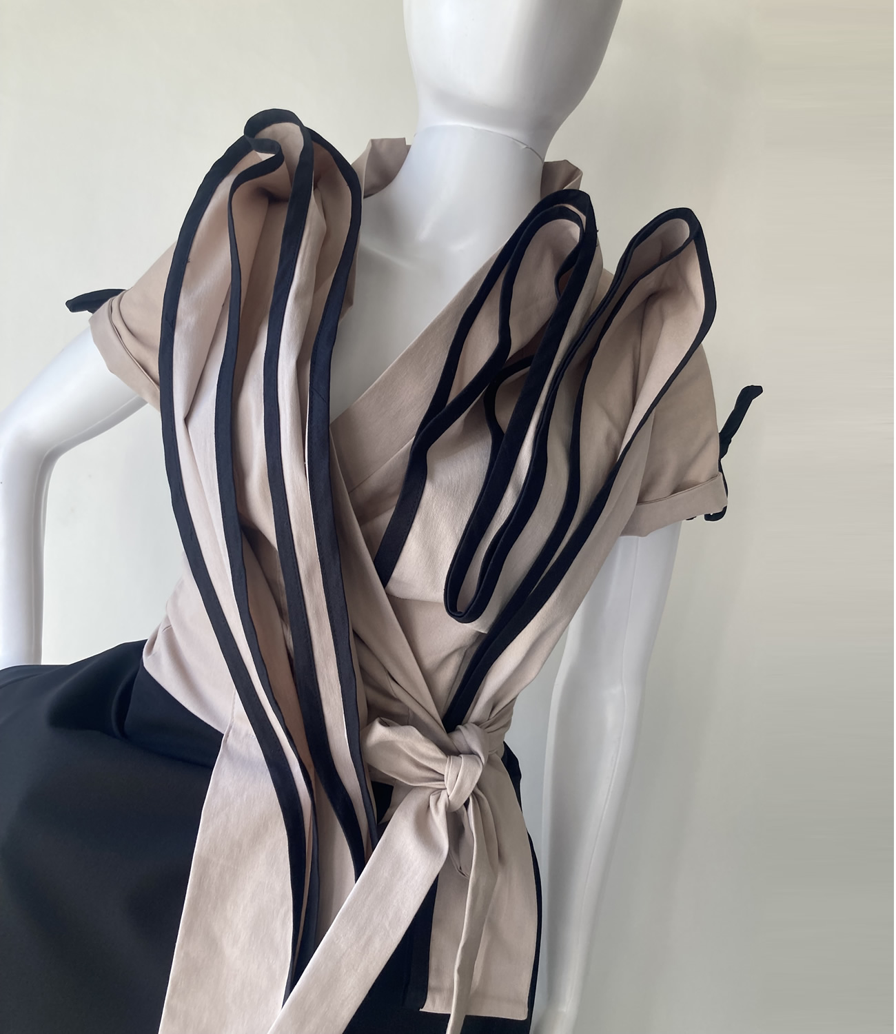 Preklopna haljina napravljena od crne i Pearl boje. Atraktivni volani aplicirani na prednjem dijelu. Džepovi u bočnim šavovima. Wrap dress made of black and pearl color. Attractive ruffles applied on the front. Pockets in the side seams.